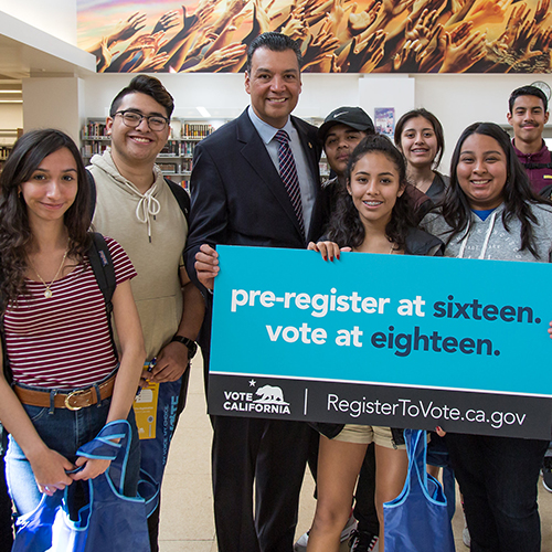 Photo of Secretary of State Alex Padilla with a group of students holding a sign that read pre-register at sixteen. vote at eighteen